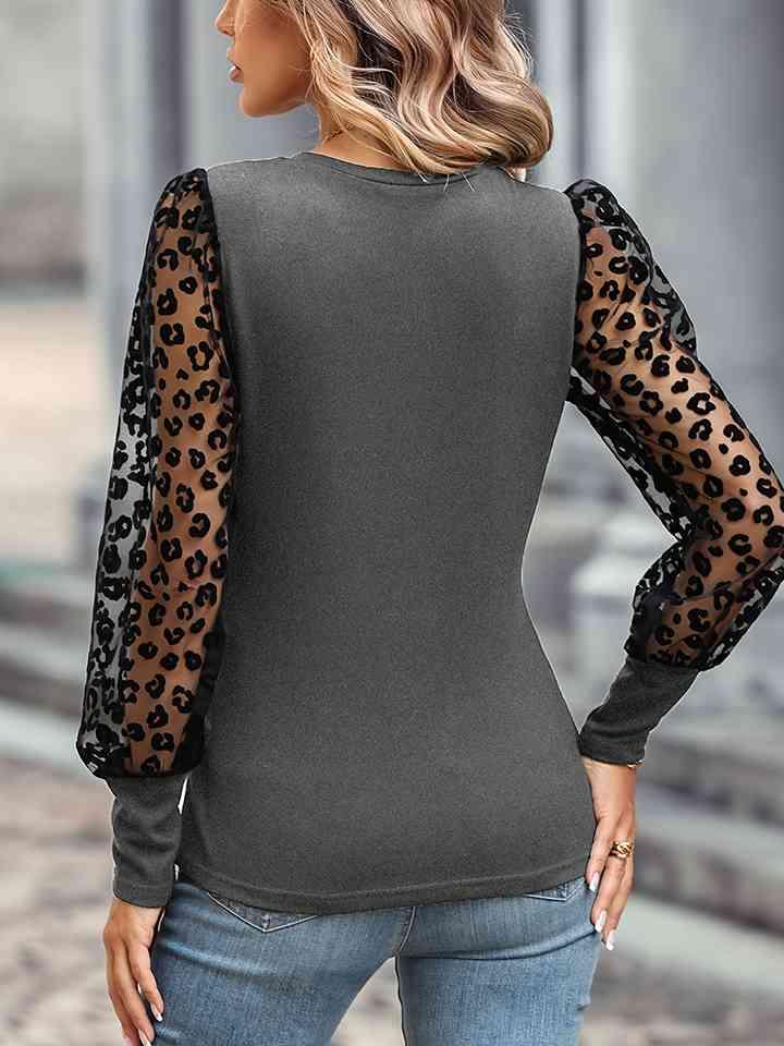 a woman wearing a black top with leopard print sleeves