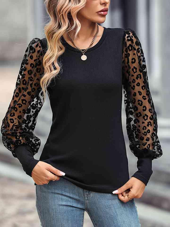 a woman wearing a black top with leopard print sleeves