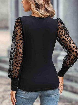 a woman wearing a black top with leopard print sleeves