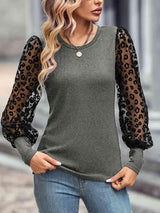 a woman wearing a grey top with leopard print sleeves