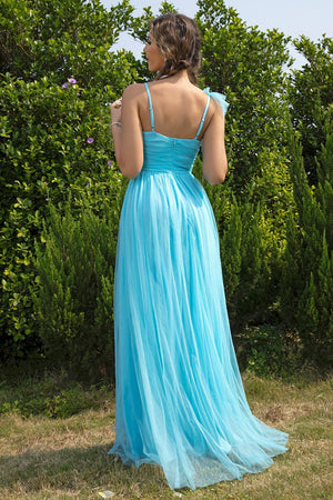 a woman in a blue dress standing in front of bushes