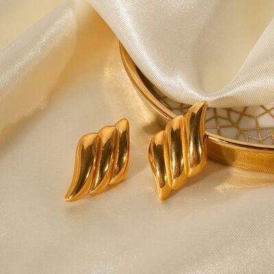 a pair of gold earrings sitting on top of a white cloth