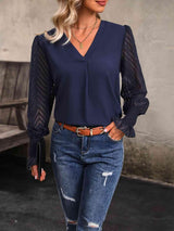 a woman wearing a blue blouse and ripped jeans