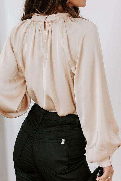 a woman wearing a beige blouse and black pants