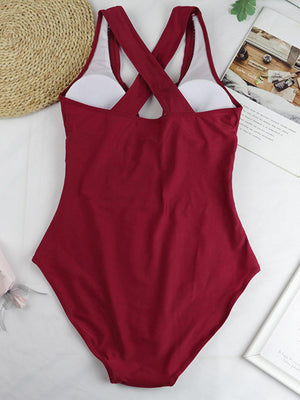 a red one piece swimsuit sitting on top of a bed