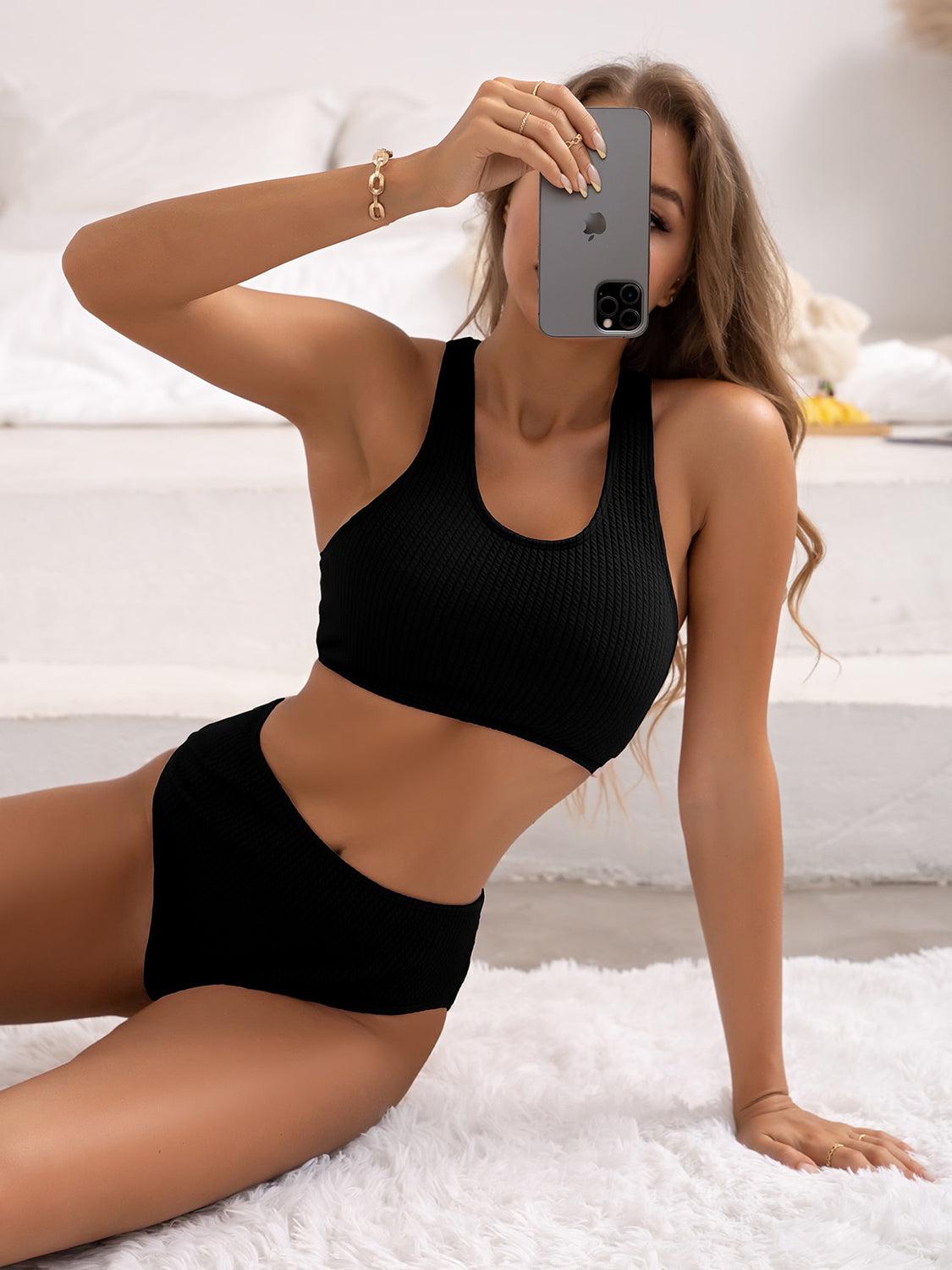 a woman in a black bikini top taking a selfie