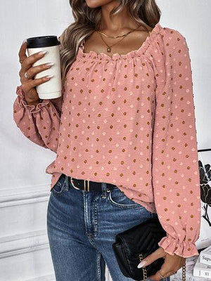 a woman holding a coffee cup and wearing a pink top