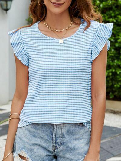 a woman wearing a blue top and ripped shorts