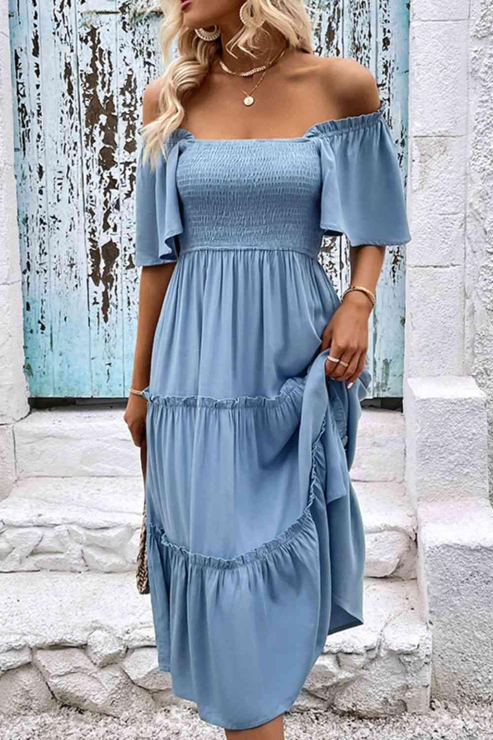 a woman wearing a blue off the shoulder dress