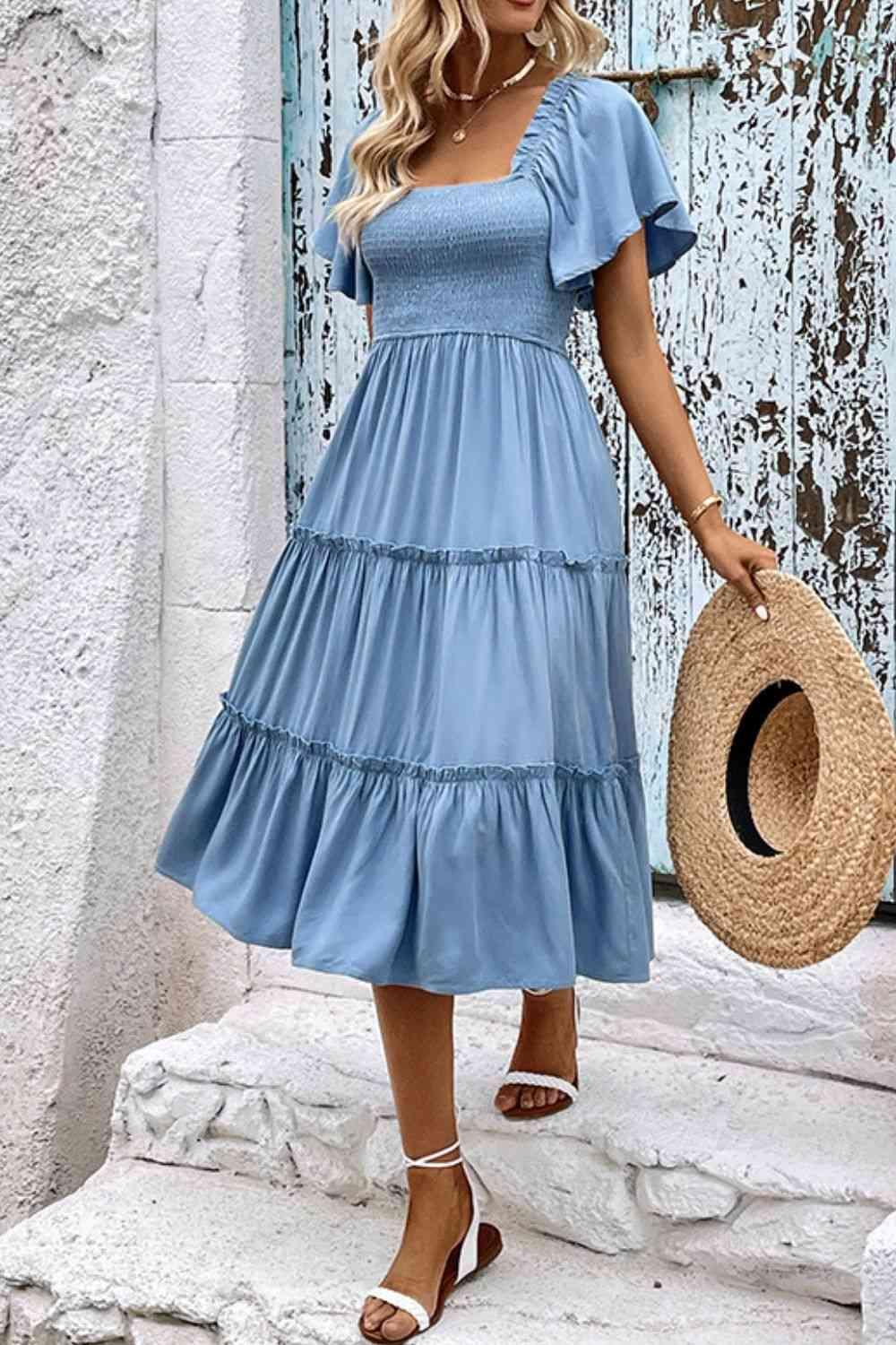 a woman wearing a blue dress and straw hat