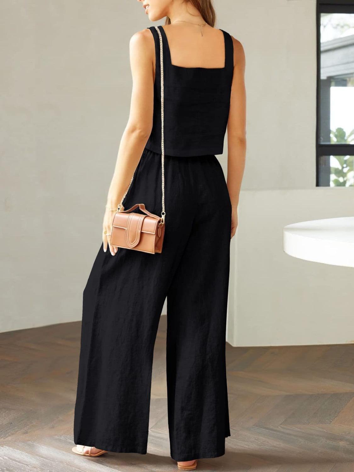 a woman in a black jumpsuit holding a purse