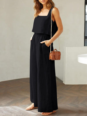 a woman in a black jumpsuit holding a brown purse