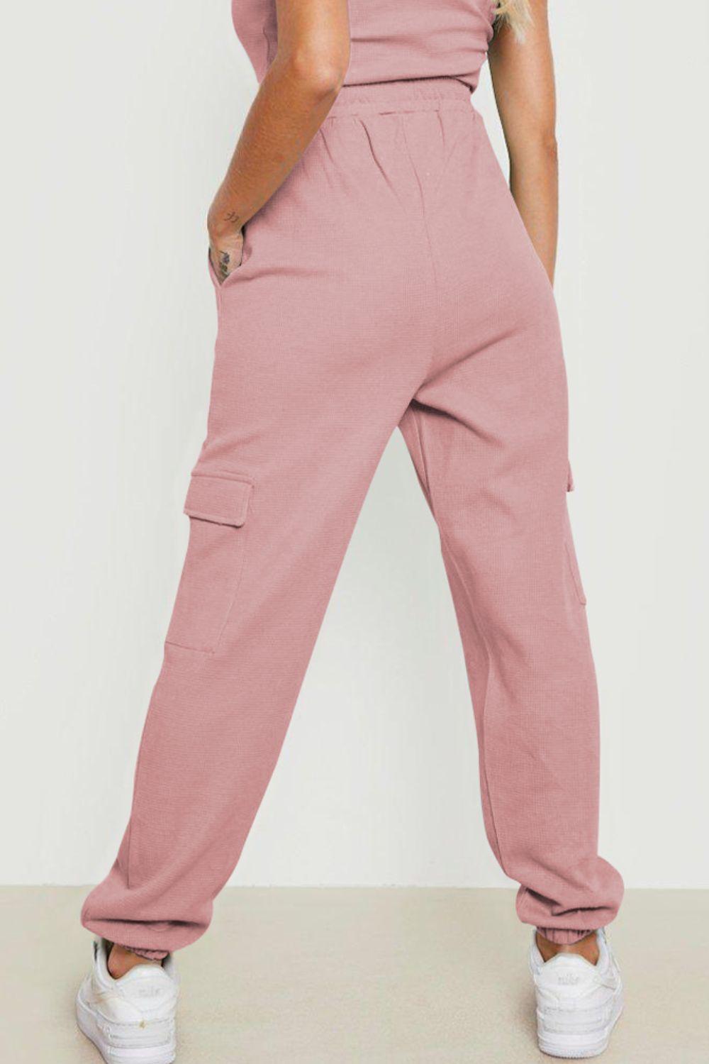 a woman wearing a pink jumpsuit and white sneakers