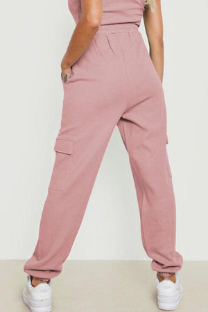 a woman wearing a pink jumpsuit and white sneakers