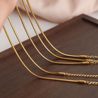 a set of gold necklaces on a wooden table