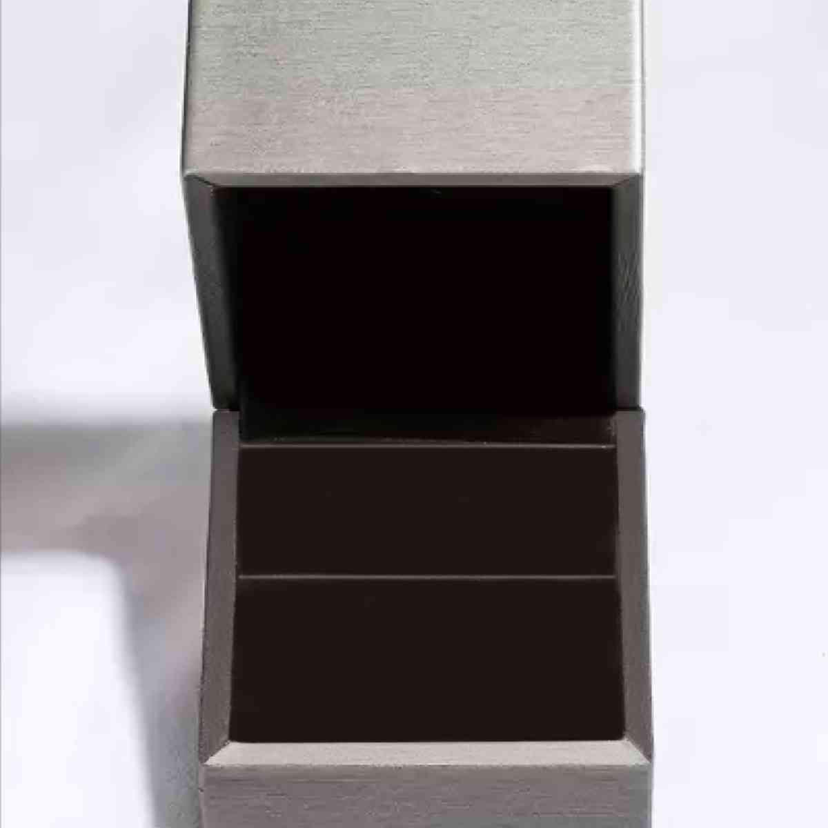 a silver box with a black lid on a white surface