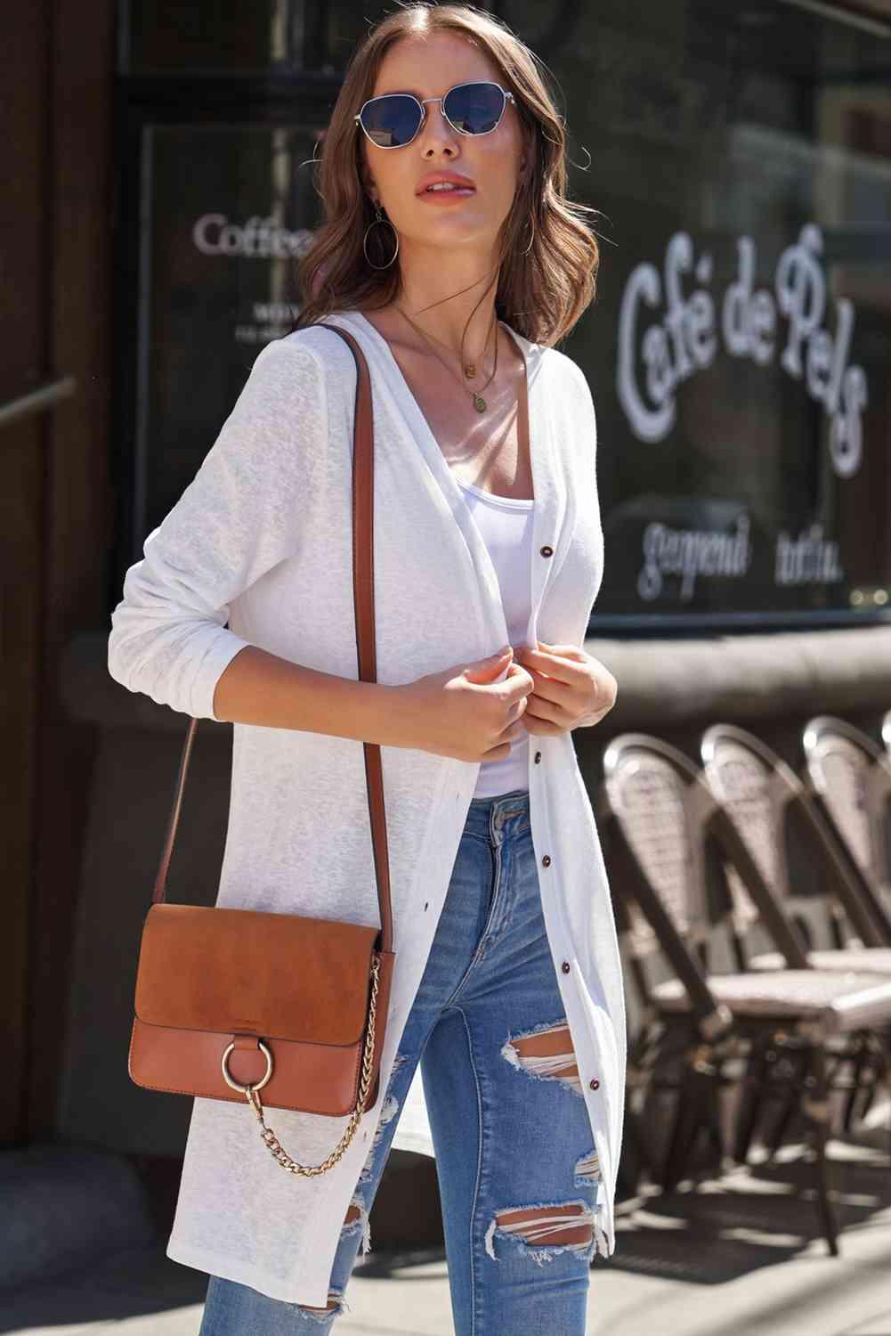 a woman wearing ripped jeans and a white cardigan