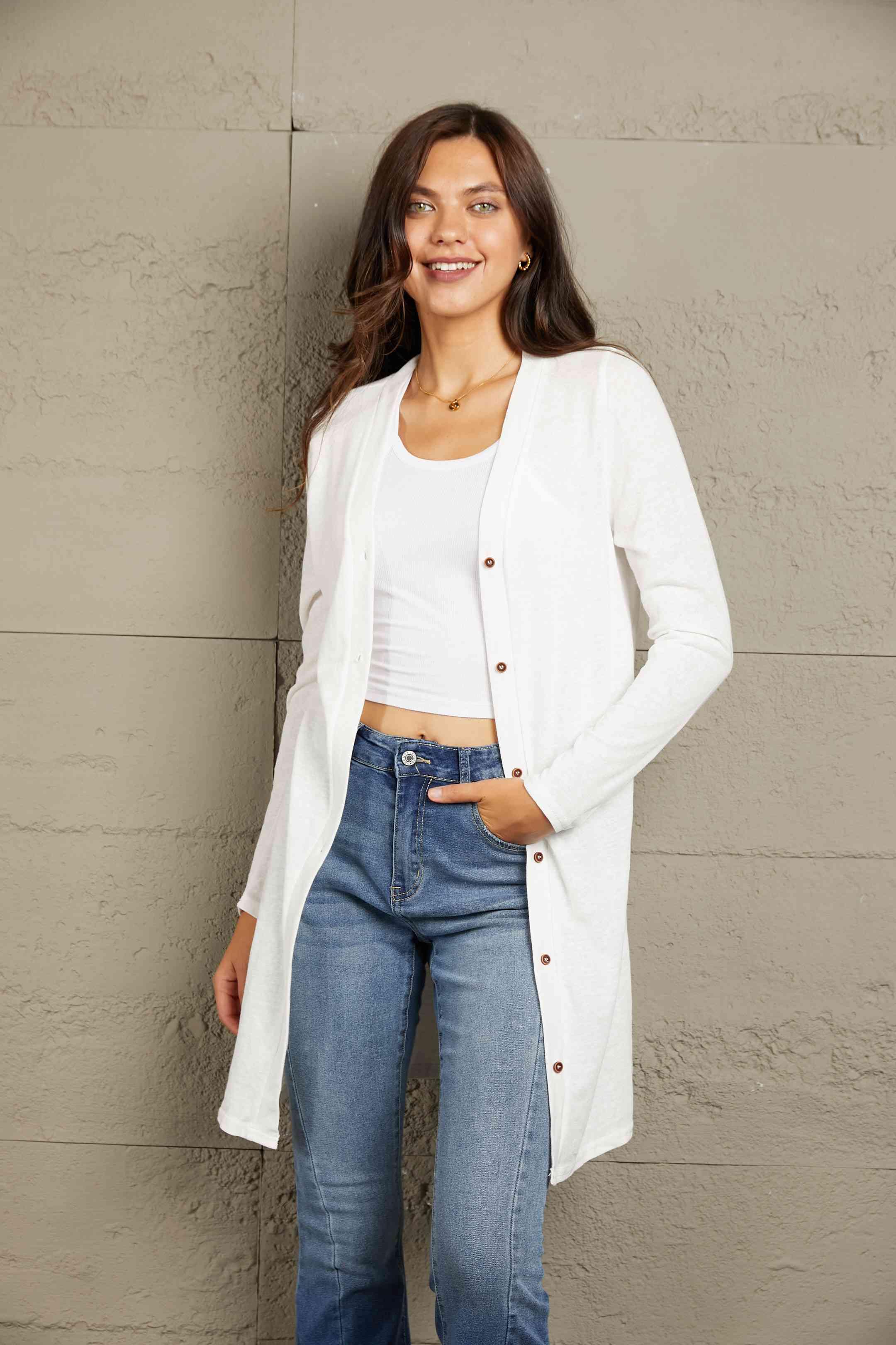 a woman wearing jeans and a white cardigan