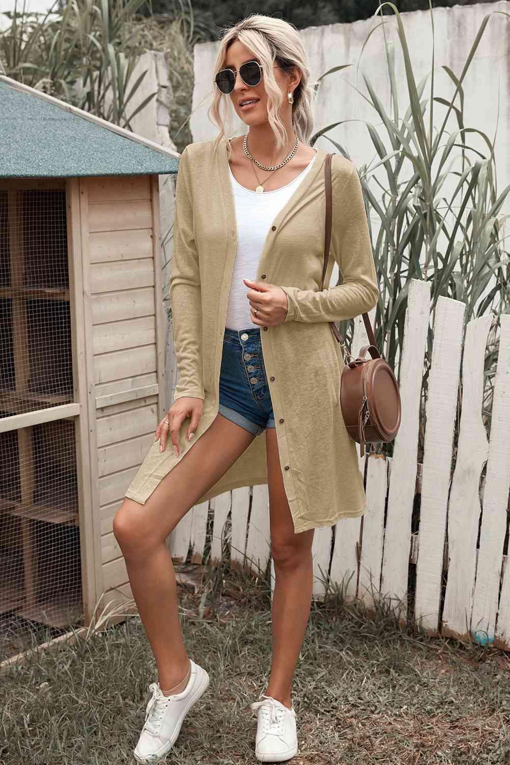 a woman wearing a tan cardigan and denim shorts