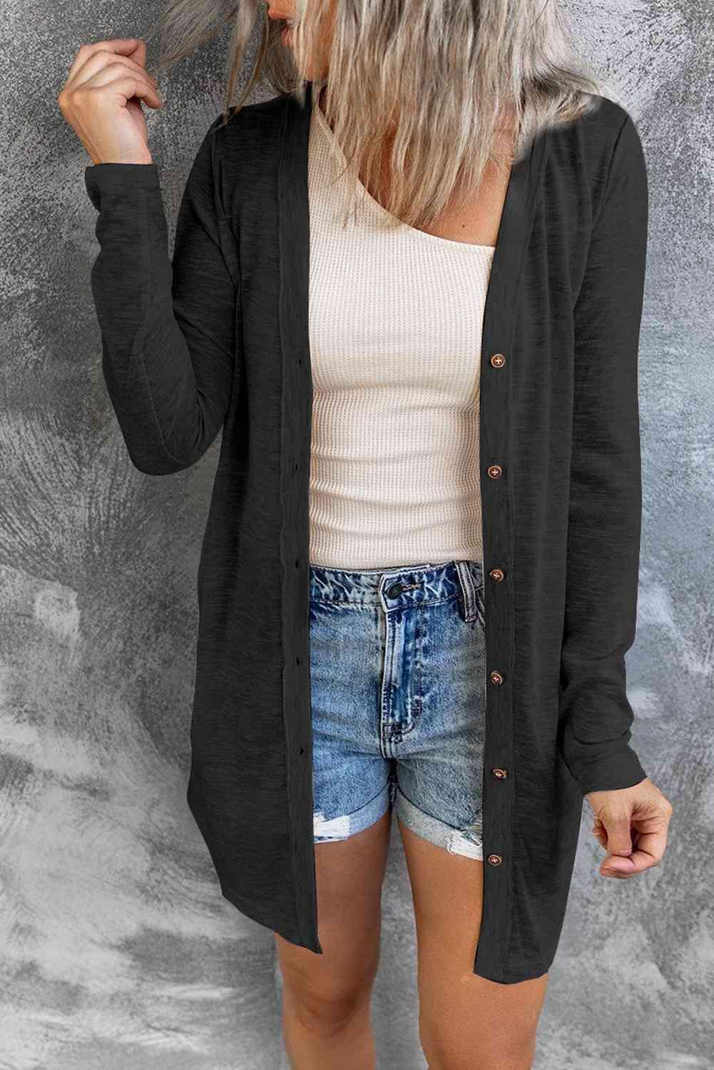 a woman wearing a black cardigan and denim shorts