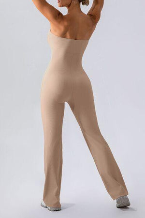 a woman in a tan bodysuit is holding her arms up