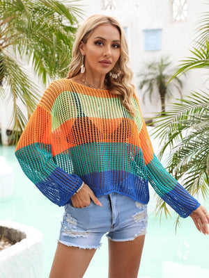 a woman standing next to a pool wearing a colorful sweater