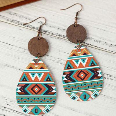 a pair of earrings with a wooden disc hanging from it