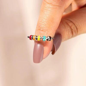 a woman's hand holding a multicolored ring
