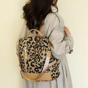 a woman is holding a leopard print backpack