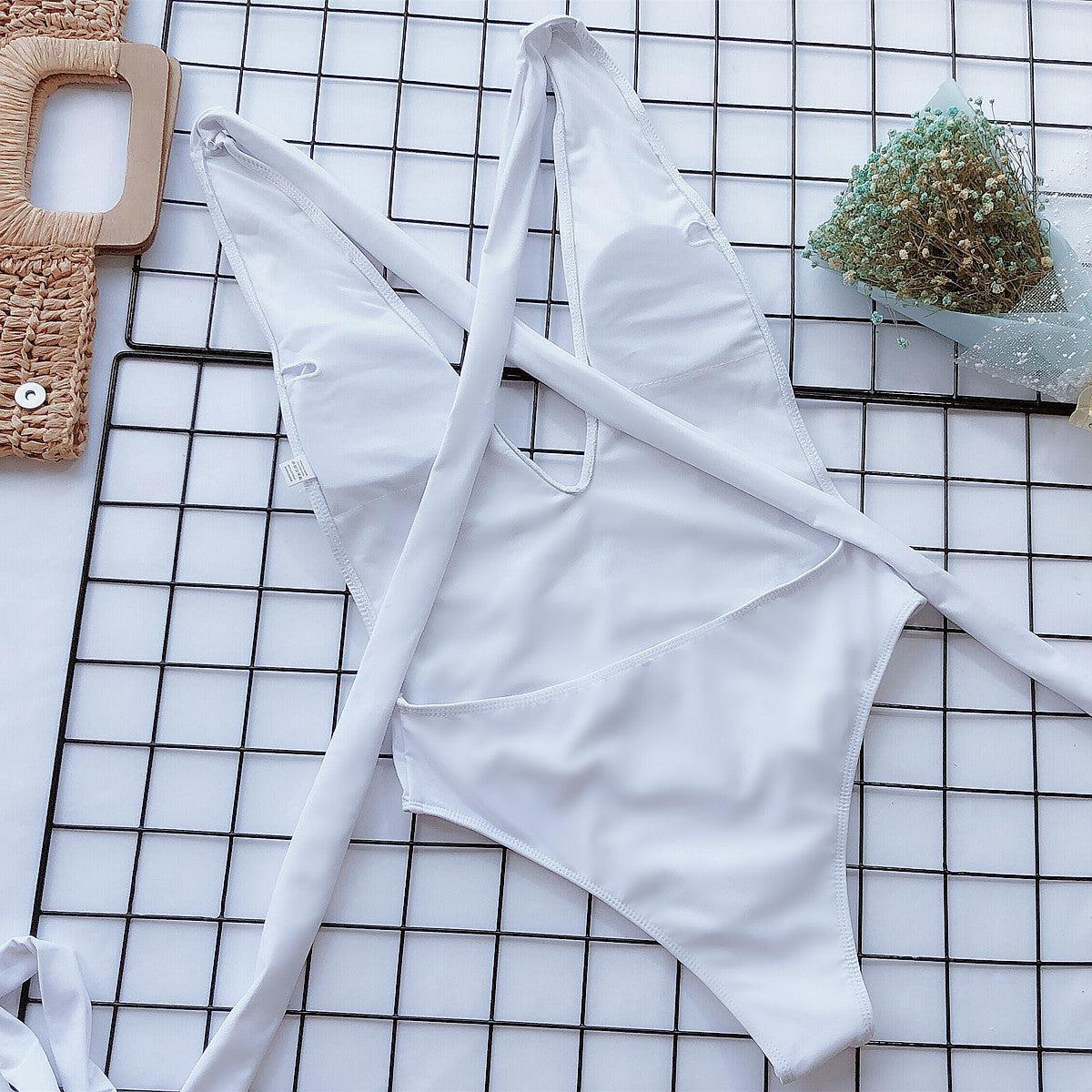 a white swimsuit laying on a tiled floor next to a potted plant