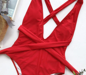 a red one piece swimsuit laying on top of a table