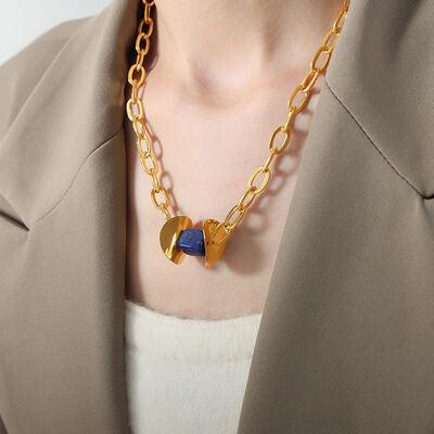 a woman wearing a gold necklace with a blue heart on it