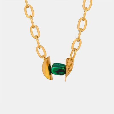 a gold chain with a green bead on it