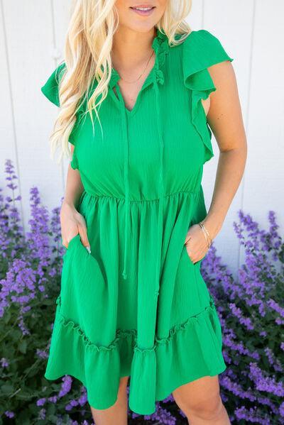 a woman in a green dress standing in front of purple flowers