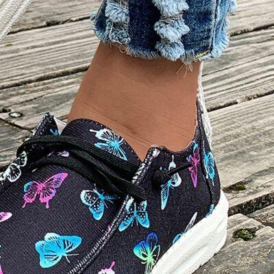 a close up of a person's foot wearing butterfly print sneakers
