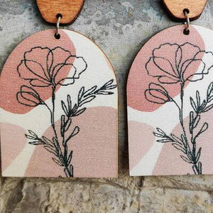 a pair of wooden earrings with flowers on them