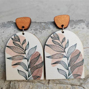 a pair of wooden earrings with leaves painted on them