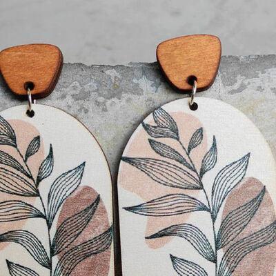 a pair of wooden earrings with leaves painted on them