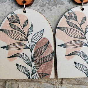 a pair of wooden earrings with leaves on them