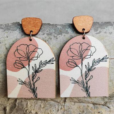 a pair of wooden earrings with flowers painted on them