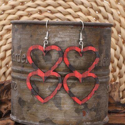 a pair of heart shaped wooden earrings sitting on top of a barrel