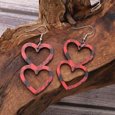 a pair of heart shaped wooden earrings on a piece of wood