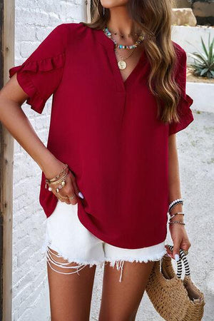 a woman wearing a red blouse and white shorts