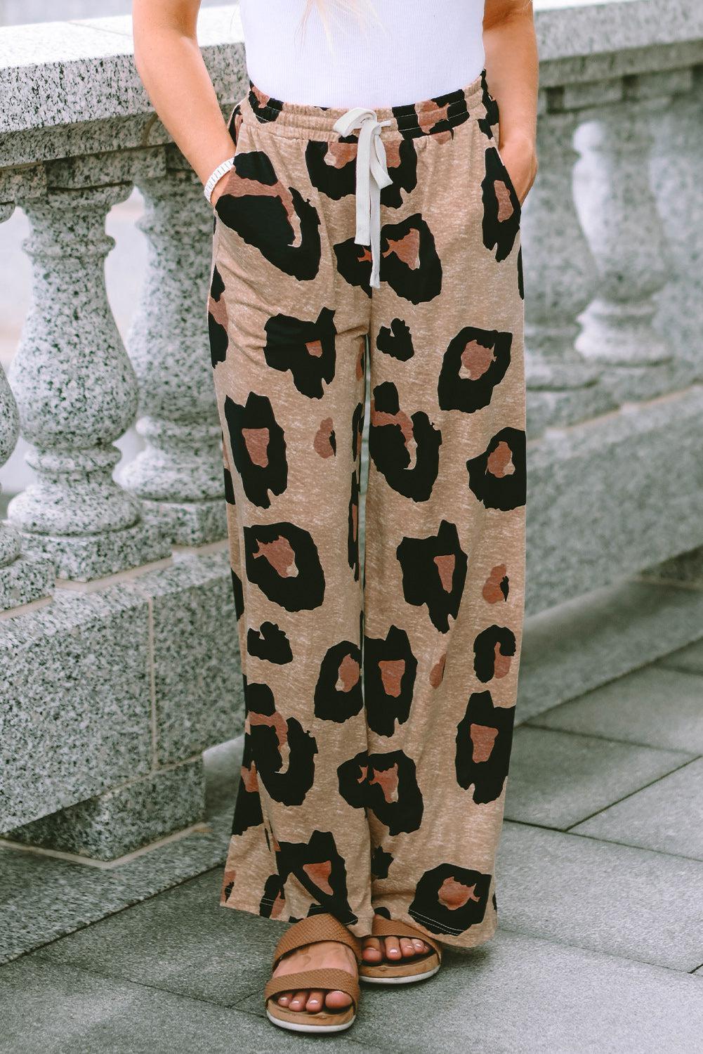 a woman standing on a sidewalk wearing a pair of leopard print pants