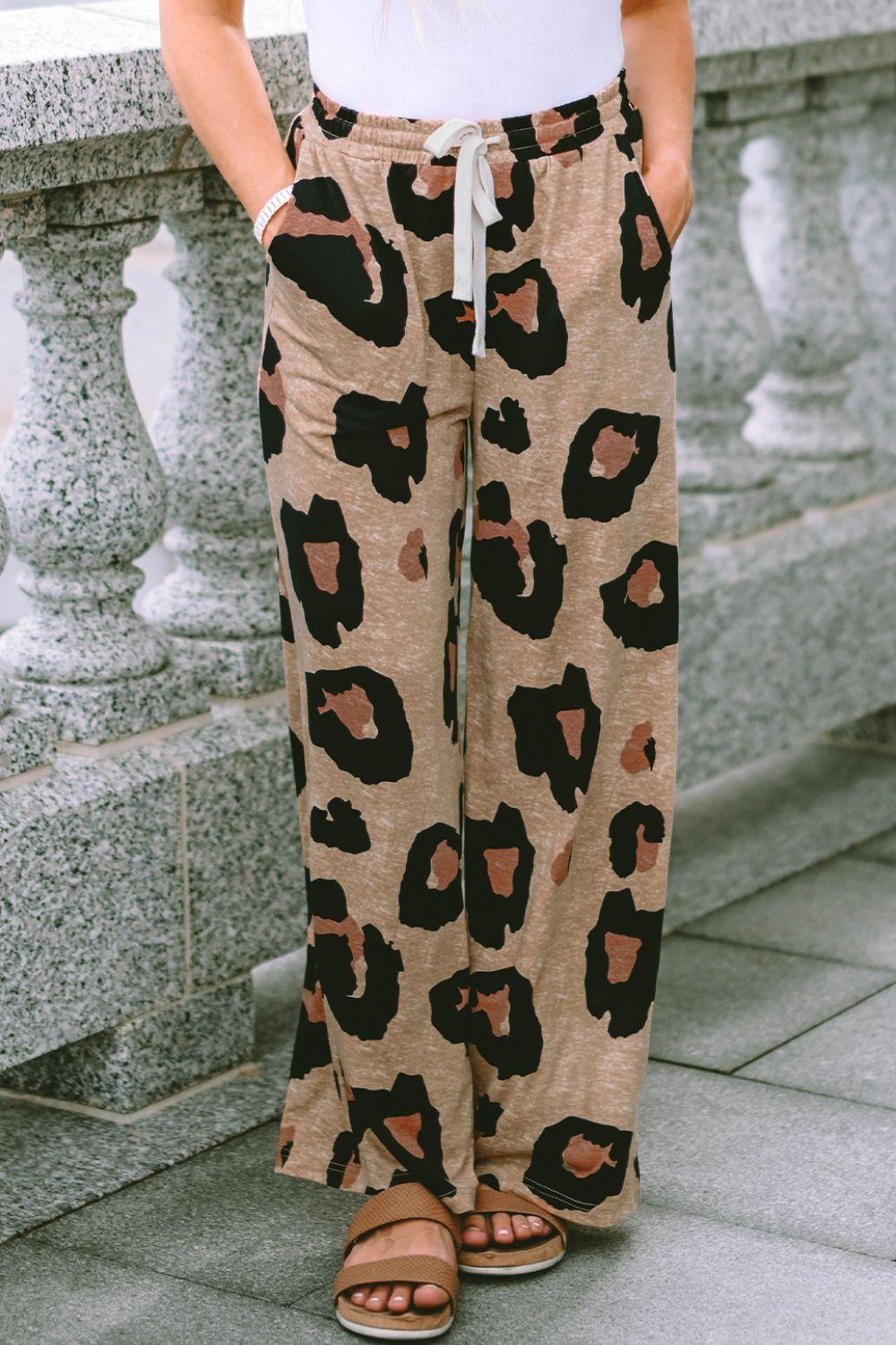 a woman standing on a sidewalk wearing a pair of leopard print pants