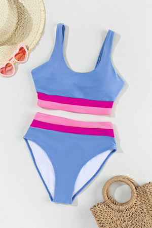 a blue and pink one piece swimsuit next to a straw bag