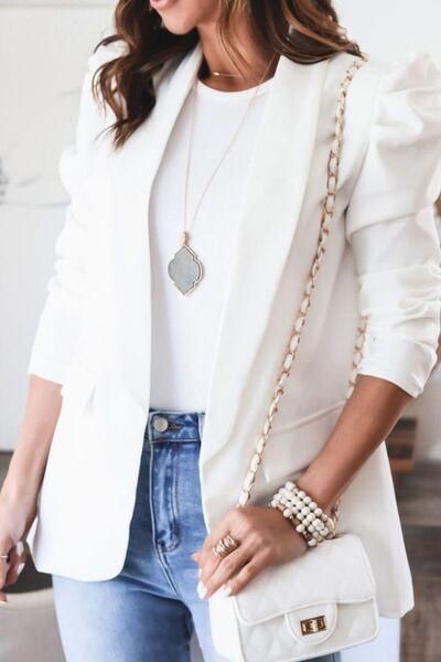 a woman wearing a white blazer and jeans