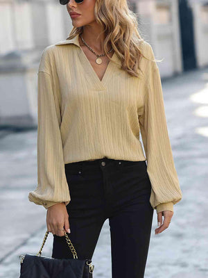 a woman wearing a tan top and black pants