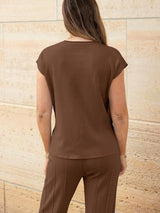 a woman wearing a brown top and brown pants