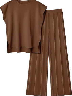 a woman wearing a brown top and pleated pants